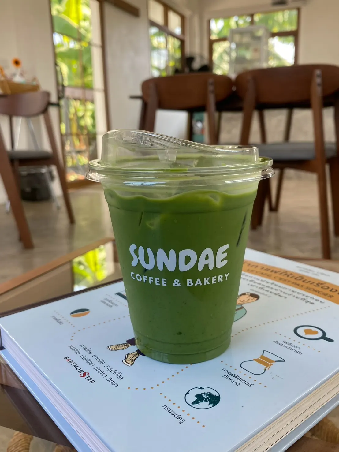 มัทฉะลาเต้เย็นในแก้ว Sundae Coffee & Bakery บนโต๊ะในร้าน